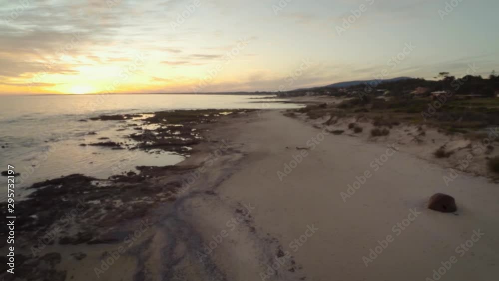 A drone shot at sunset of Playa Hermosa, in Piriapolis, Maldonado, Uruguay. The drone flies low over the calm water rippling to the shoreline in the calm evening. A drone shot at sunset of Playa Hermosa, in Piriapolis, Maldonado, Uruguay. The drone flies low over the calm water rippling to the shoreline in the calm evening.