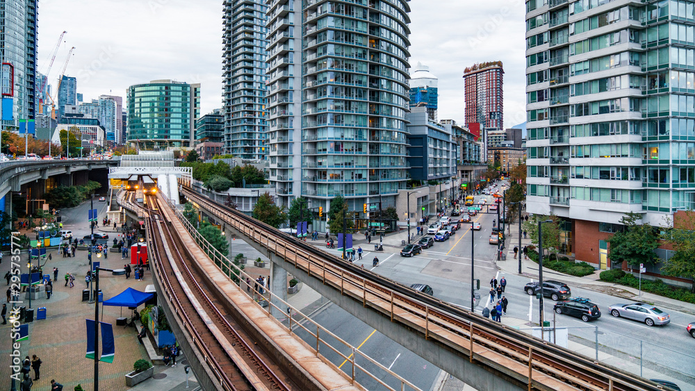 Naklejka premium Downtown Vancouver. Skytrain in Downtown Vancouver, with people just about attending to a game on the city`s arena.