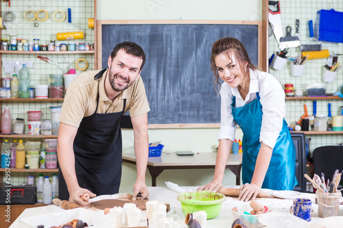 Pottering Concept. Two Happy Professional Ceramists or Claymakers During a Process of Clay Preparation on Tables in Workshop. photo