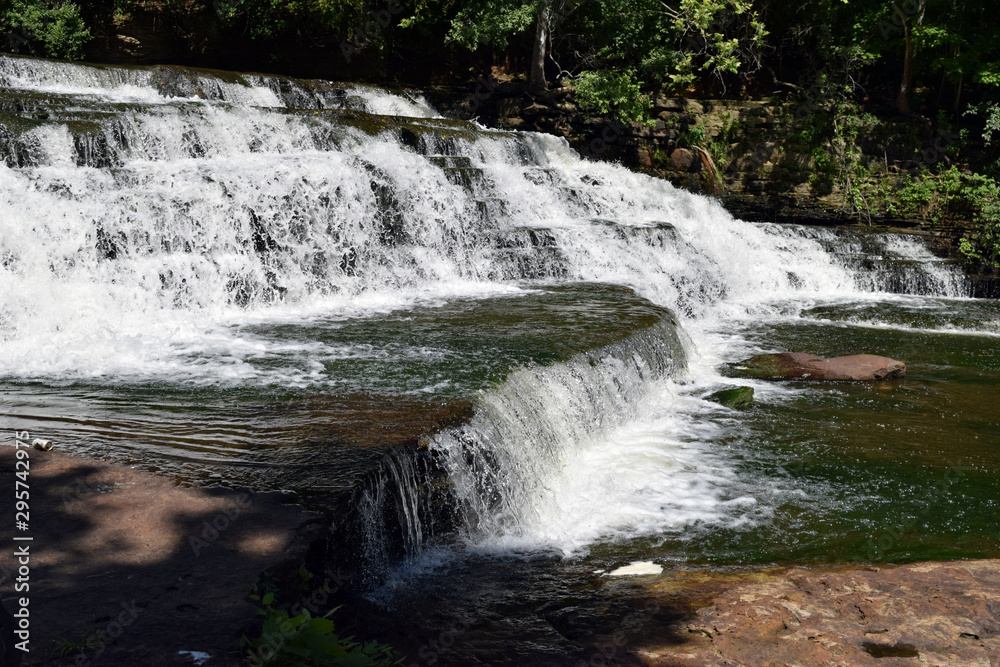 Fototapeta premium Multiple waterfalls flowing over different levels of rock.