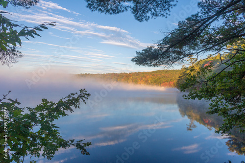 Mist lifting from a pond to reveal color fall foliage photo