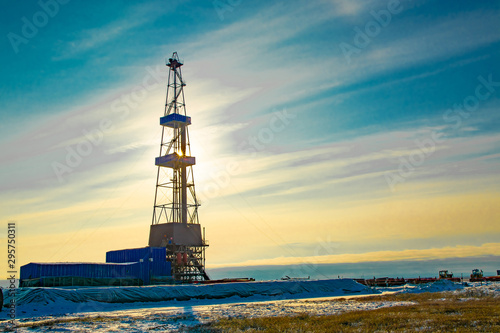 Oil and gas drilling rig in the northern tundra. The beginning of winter in the Arctic. The sun sparkles through the oil derrick.