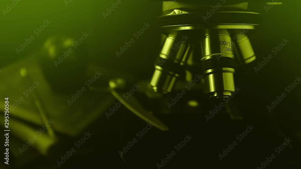 Microscope for science research at school, the study of biology and chemistry. Hand with a pencil writes down the results of the analysis, green tone. Microscope for science research at school, the study of biology and chemistry. Hand with a pencil writes down the results of the analysis, green tone.