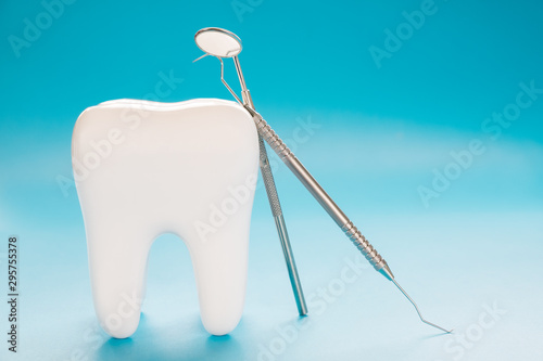 Big tooth and dentist tool on blue background. © sujit