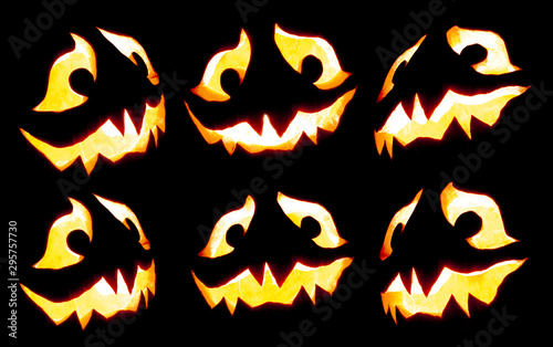 Collection of scary Halloween pumpkin Jack o lantern faces glowing red and yellow eerily on black