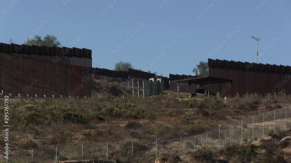 The U.S. Mexico border wall between San Diego and Tijuana looking south with Border Patrol truck mounted with surveillance camera looking east next to an opening in the wall. The U.S. Mexico border wall between San Diego and Tijuana looking south with Border Patrol truck mounted with surveillance camera looking east next to an opening in the wall.