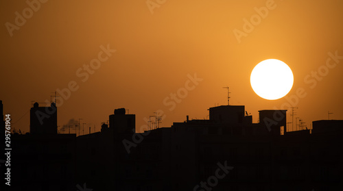 A sunset with a silhouette of some buildings and antennas
