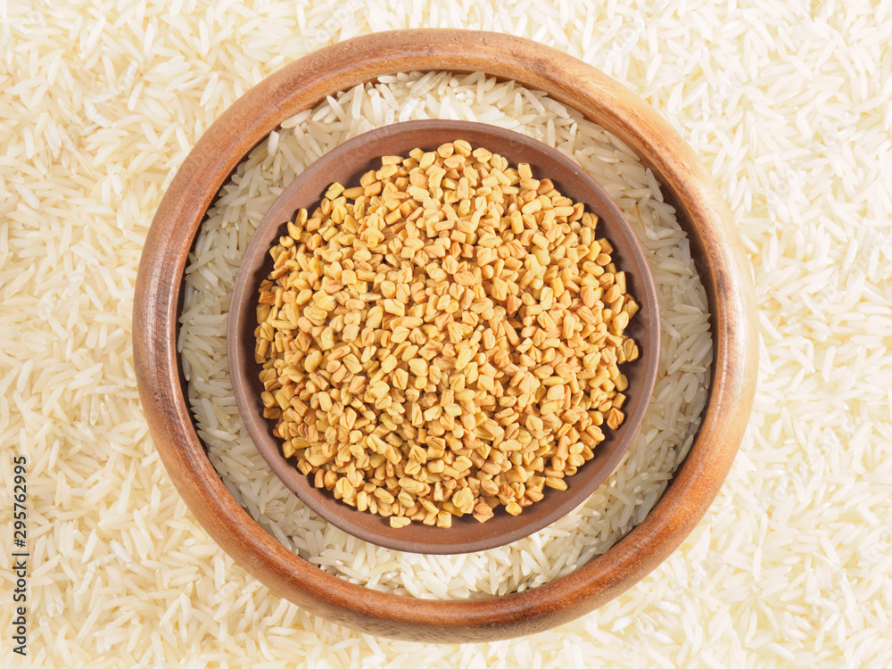 Rice in bowl and fenugreek in clay, plate. Background from basmati rice. Indian cuisine ingredients Rice in bowl and fenugreek in clay, plate. Background from basmati rice. Indian cuisine ingredients