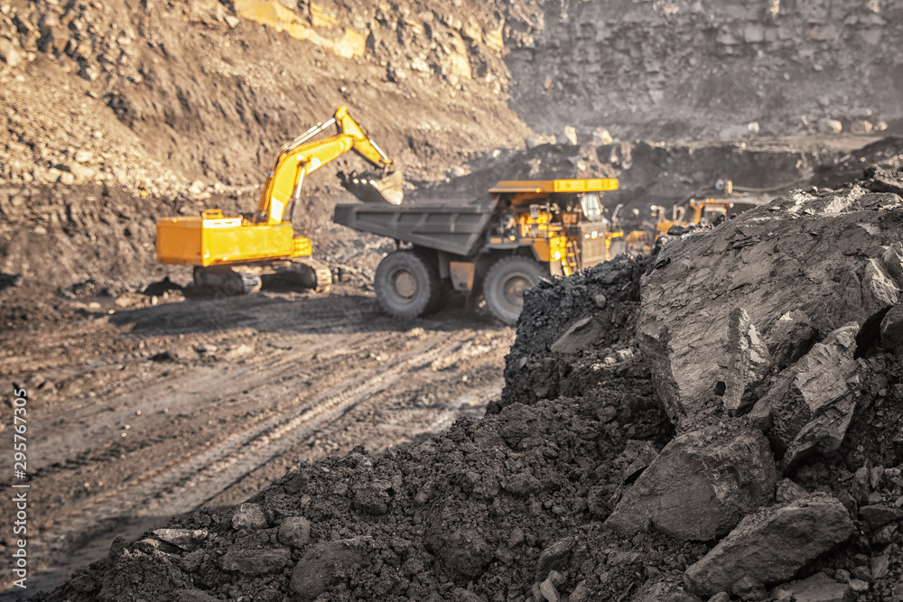 Coal open pit mine. In background blurred loading anthracite minerals excavator into large yellow truck