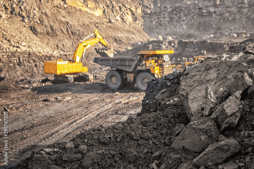 Coal open pit mine. In background blurred loading anthracite minerals excavator into large yellow truck