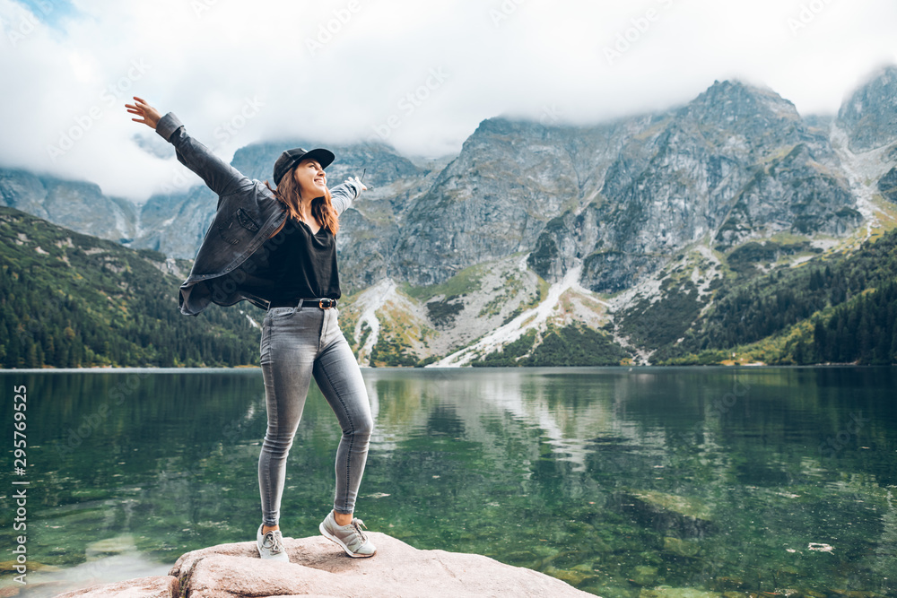 happy woman hands up looking at lake in mountains - obrazy, fototapety, plakaty 