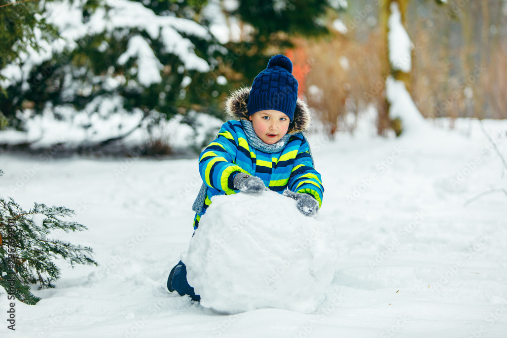 little cute boy making snowman. rolling big snowball little cute boy making snowman. rolling big snowball