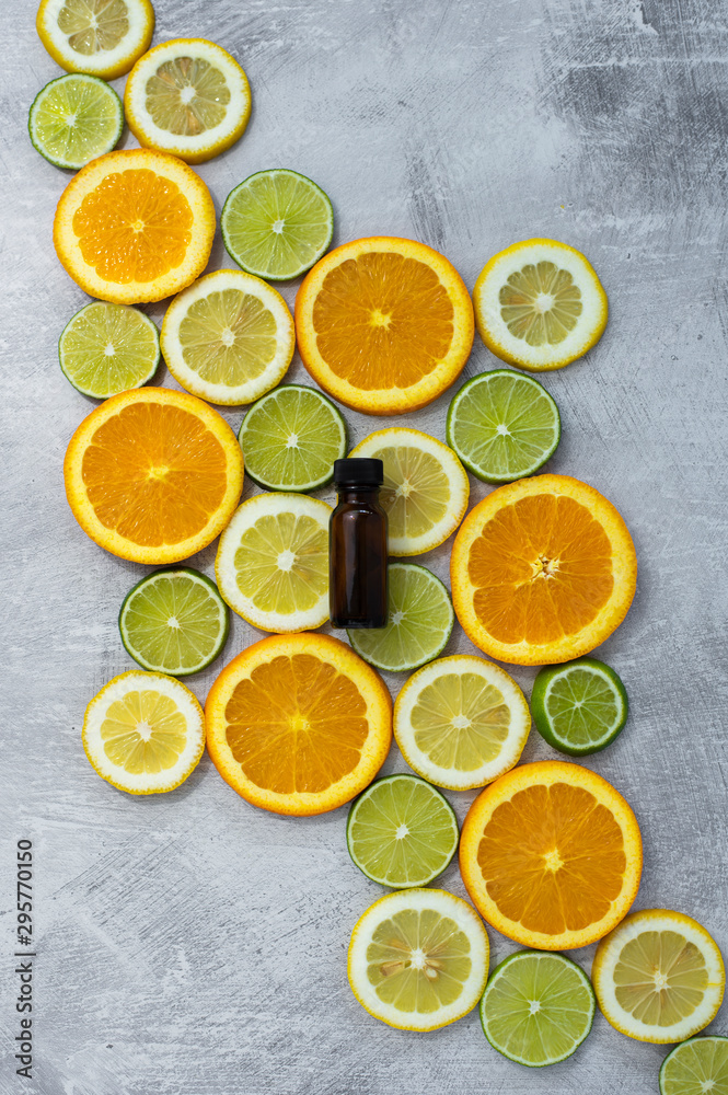 sliced oranges, lemons, and limes with essential oil bottles, amber bottles for aromatherapy oil, citrus rounds in lines on light background, copy space, copyspace sliced oranges, lemons, and limes with essential oil bottles, amber bottles for aromatherapy oil, citrus rounds in lines on light background, copy space, copyspace