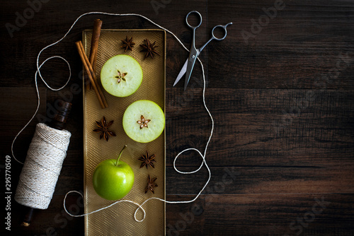 apple star with star anise, cinnamon sticks, roll of twine, and scissors, green apple sliced horizontal to show the core star, holiday still life, copyspace, copy space, recipe mulled spiced cider