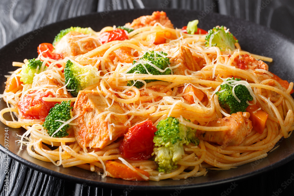 Spaghetti pasta with broccoli, chicken and pumpkin in tomato sauce close-up on a plate on the table. horizontal Spaghetti pasta with broccoli, chicken and pumpkin in tomato sauce close-up on a plate on the table. horizontal