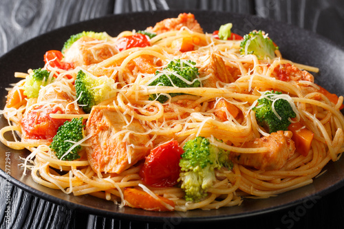 Spaghetti pasta with broccoli, chicken and pumpkin in tomato sauce close-up on a plate on the table. horizontal