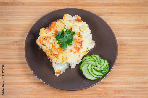 Cauliflower and seafood gratin portion on brown dish, top view