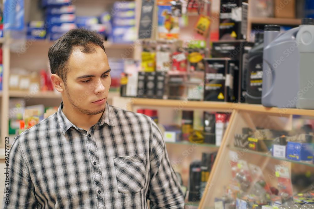 young man looking at shop window in auto parts store