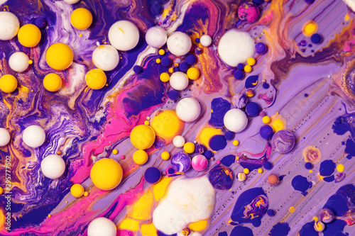 Acrylic paint balls abstract texture. Purple, blue and yellow liquids mix. Creative multicolor background. Bright colors fluid, flowing wallpaper design. Mixed pigments colourful backdrop.