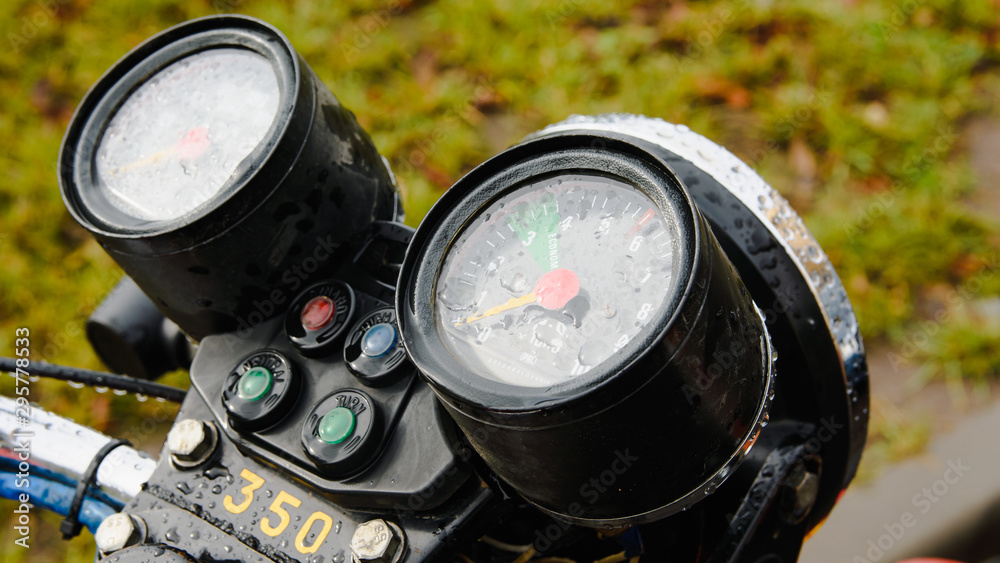 Naklejka premium motorcycle speedometer with raindrops close up on grass background
