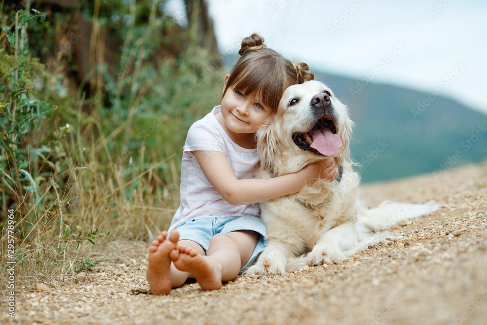 A child with a dog. Little girl plays with a dog in nature.  - obrazy, fototapety, plakaty 