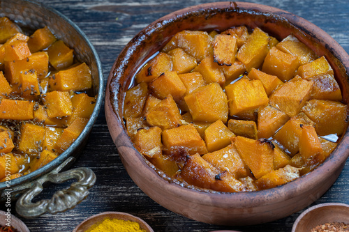 Baked yellow pumpkin with honey, anise, olive oil and spices on a plate on the wooden table. Vegetarian food. Closeup