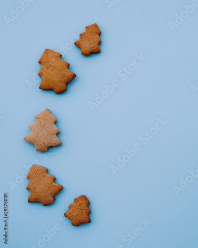 Holiday cookies in the shape of Christmas tree on light blue background. Copy space. Flat lay, minimal composition. Festive pastry. New year postcard