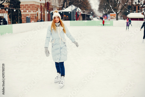 Girl in a winter park. Beautiful lady in a blue jacket. Woman in a ice arena