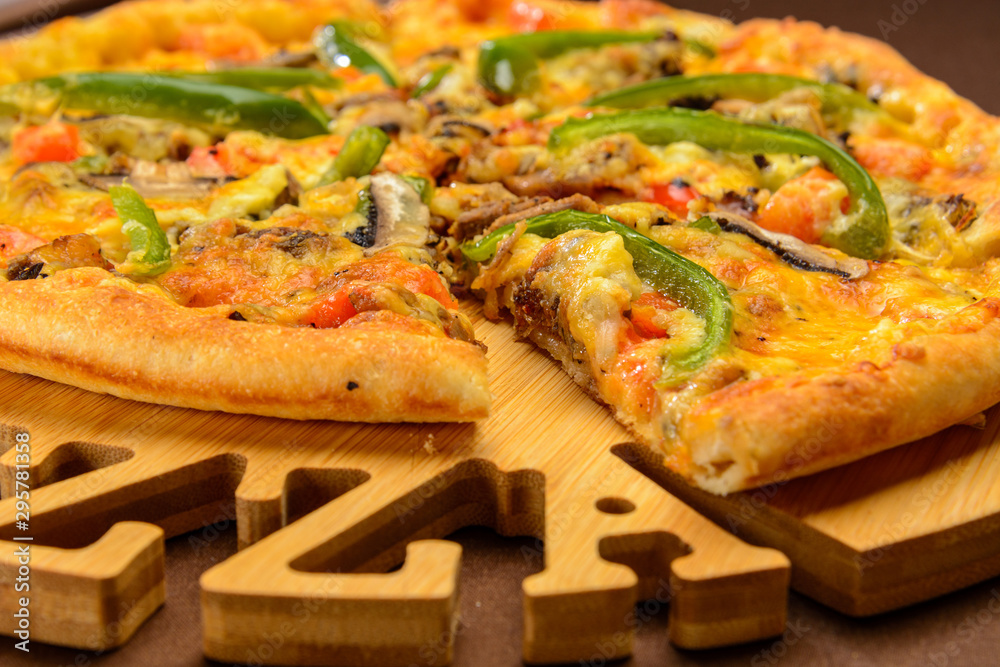 Meat pizza with green pepper on the wooden board. One piece cut off Meat pizza with green pepper on the wooden board. One piece cut off