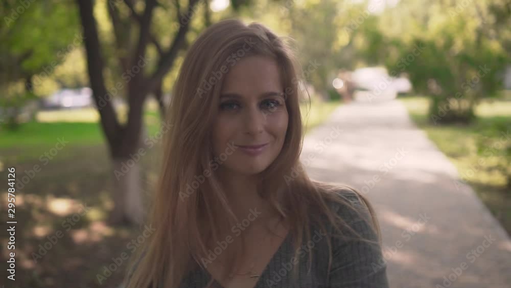 Cute young girl in the park among the trees. Happy girl in a gray dress smiling and flirting. Close-up. Cute young girl in the park among the trees. Happy girl in a gray dress smiling and flirting. Close-up.