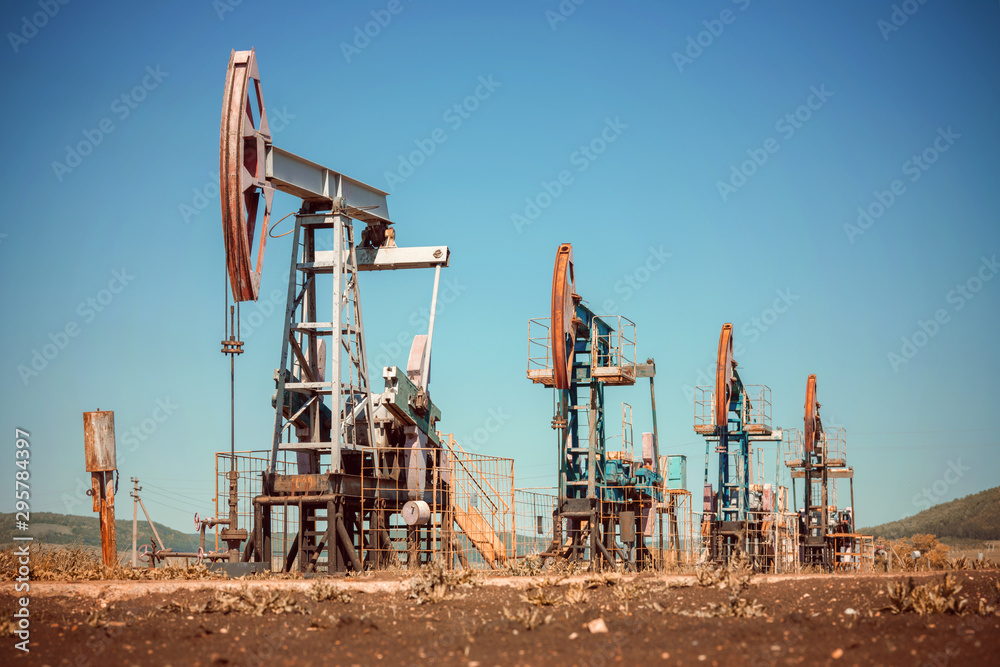 Oil pump jack rocking with pipeline in the background. Rocking machines for power generation. Extraction of oil Oil pump jack rocking with pipeline in the background. Rocking machines for power generation. Extraction of oil