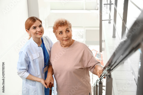 Nurse assisting elderly woman on stairs indoors