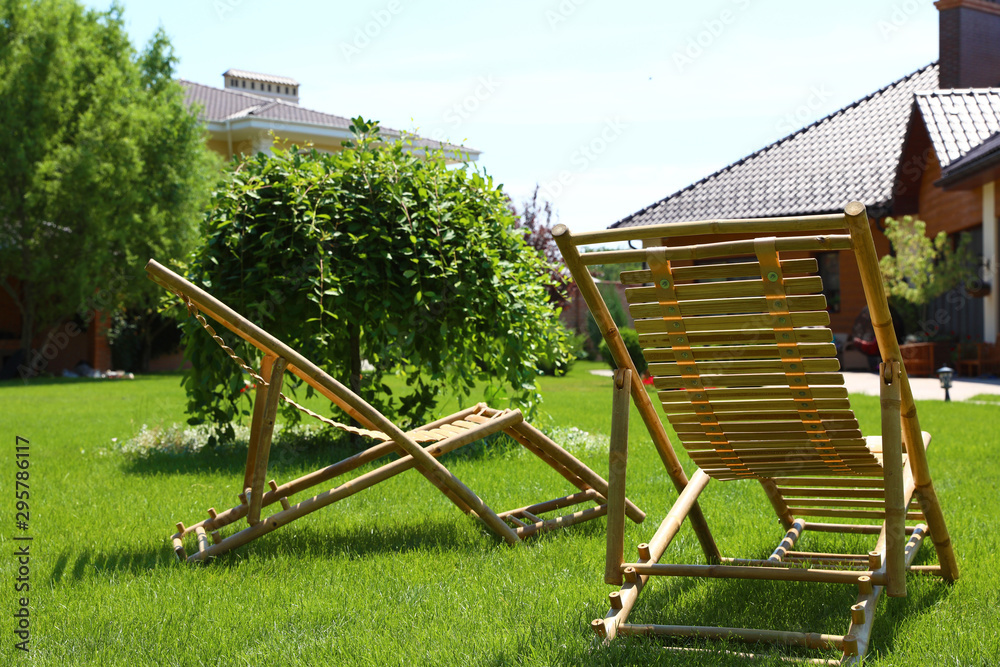 Wooden deck chairs in beautiful garden on sunny day Wooden deck chairs in beautiful garden on sunny day