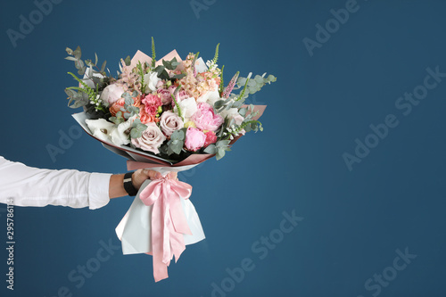 Fényképezés Man holding beautiful flower bouquet on blue background, closeup view