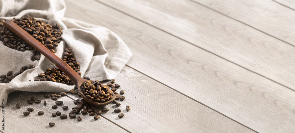 Fresh roasted coffee beans with spoon and burlap sack on a wooden surface, in panorama wide banner template for web, print, or advertising Fresh roasted coffee beans with spoon and burlap sack on a wooden surface, in panorama wide banner template for web, print, or advertising