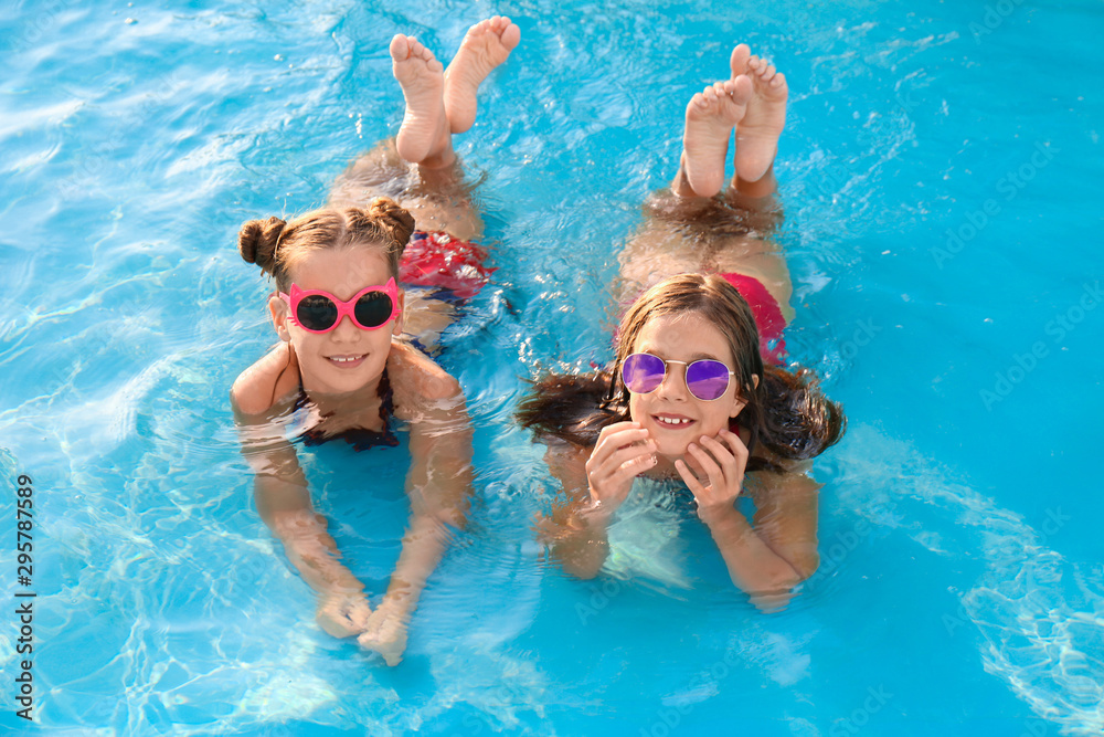 Happy cute girls in swimming pool on sunny day