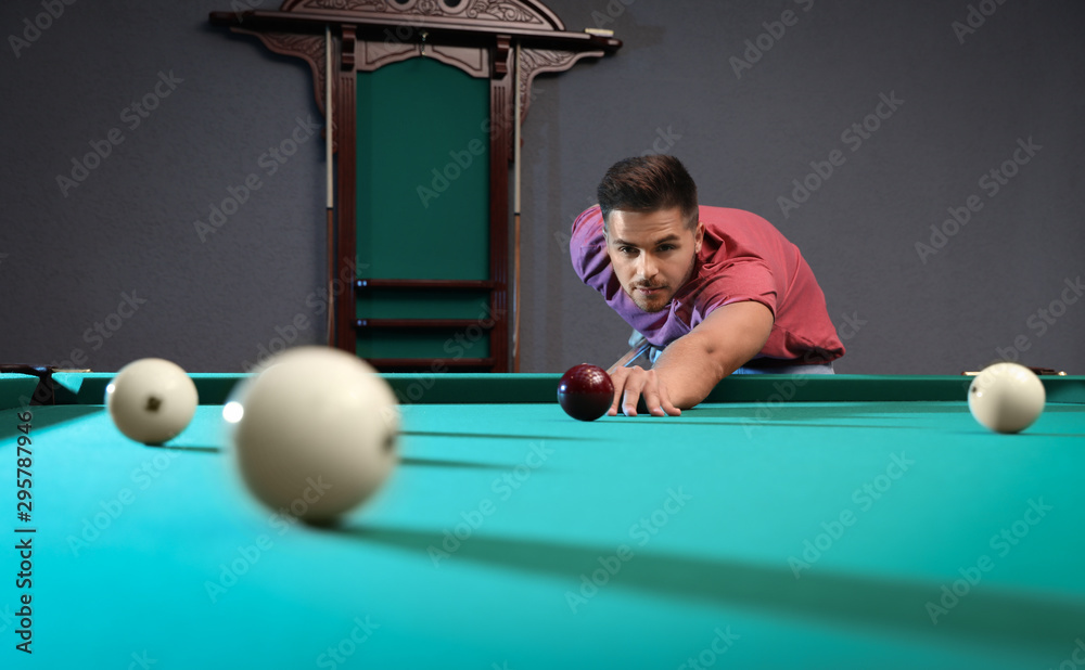 Fototapeta premium Handsome young man playing Russian billiard indoors
