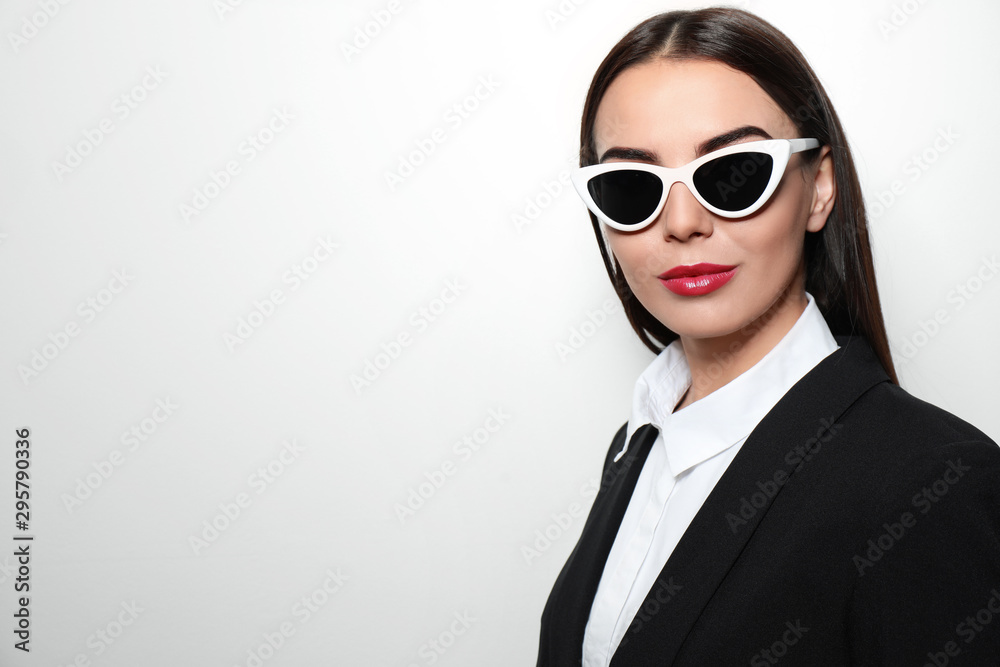 Young businesswoman in stylish sunglasses on light background, space for text Young businesswoman in stylish sunglasses on light background, space for text