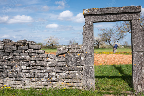 L'entrée d'un verger. Un homme dans un jardin. Entrée et muret en pierres sèches dans un jardin de campagne. Héritage historique. Porte en pierre dans un jardin. Verger de fruitiers. photo