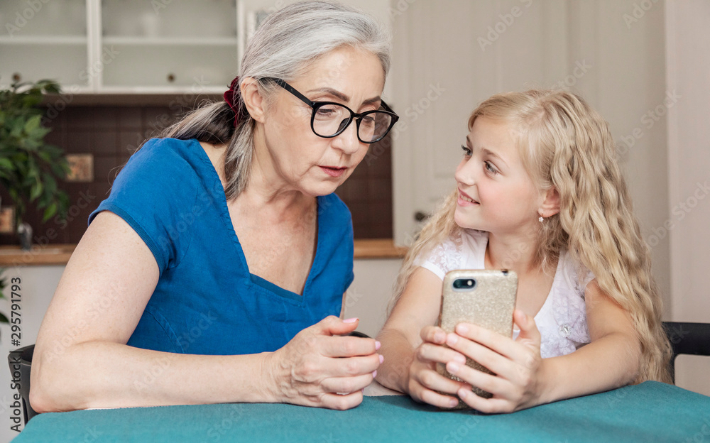 Preschool female kid teaching her grandmother some smartphone tips and tricks Preschool female kid teaching her grandmother some smartphone tips and tricks