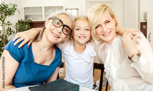 Slika na platnu Portrait of cheerful young blonde woman with her dearest mother and daughter in