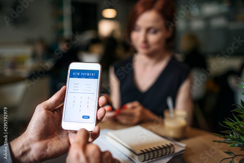 Midsection of businesspeople with smartphone in a cafe, checking finances.