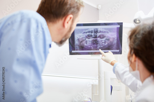 Zahnarzt erklärt einem Patient Röntgenaufnahme