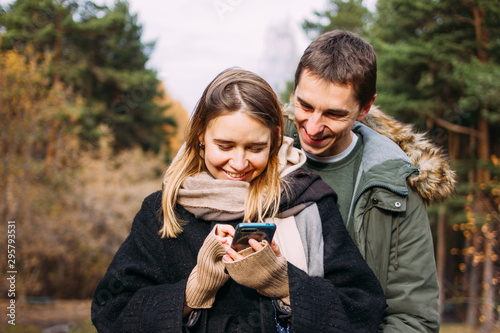 Happy young couple in love friends travellers dressed in casual style using mobile on nature park forest © Galina Zhigalova