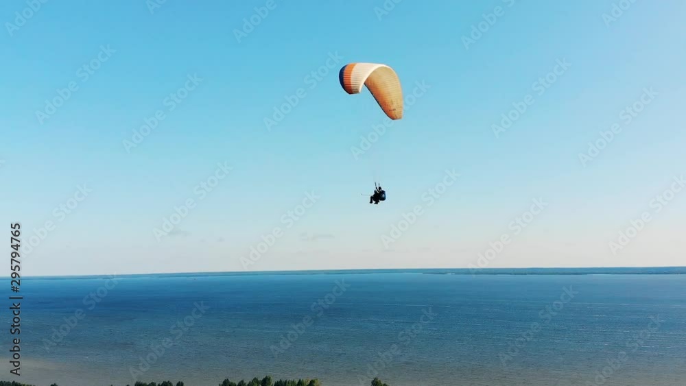 Two people are flying above the water on the paraplane Two people are flying above the water on the paraplane