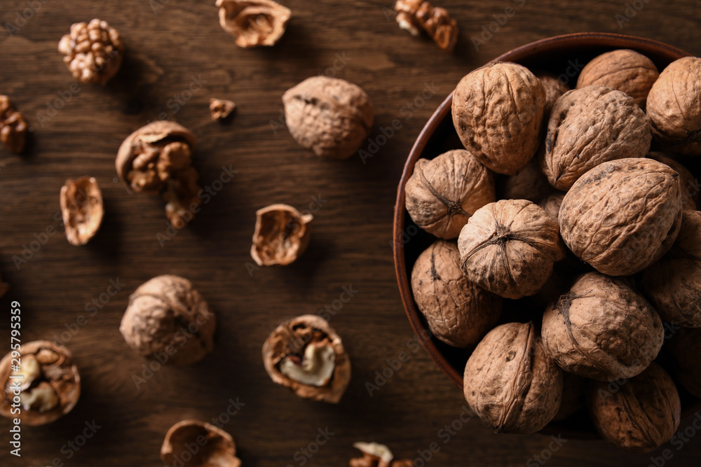 Walnuts nuts in a bowl on a dark brown wooden background in a dark key Walnuts nuts in a bowl on a dark brown wooden background in a dark key