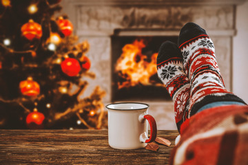 Woman legs with christmas socks and fireplace in home interiro 