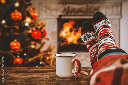 Woman legs with christmas socks and fireplace in home interiro  photo