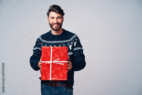 Happy man giving Christmas present, isolated on gray background.