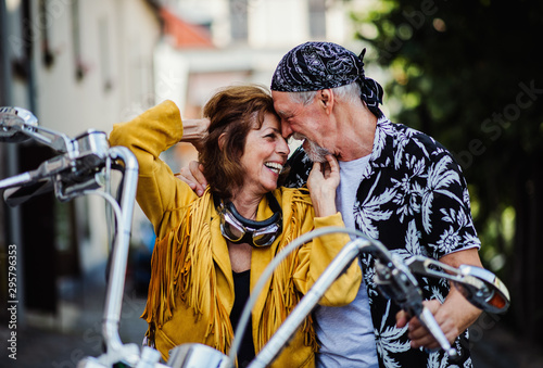 A cheerful senior couple travellers in love with motorbike in town.